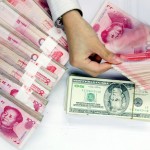 Un empleado cuenta montones de yuanes y dólares en un banco en Shanghai, China.