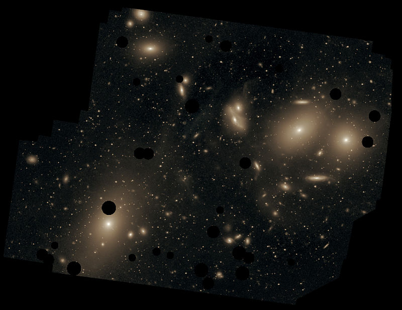 Imagen de gran tiempo de exposición de la región central del cúmulo de Virgo en la que se puede apreciar la luz difusa que existe entre las galaxias de éste, producida por estrellas intergalácticas. Los discos negros corresponden a estrellas que han sido eliminadas en la imagen. La galaxia más grande y brillante es la M87 abajo a la izquierda. (Chris Mihos (Case Western Reserve University)/ESO/Wikimedia Commons)